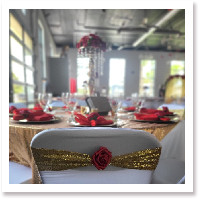 Table display inside Riverbrook events venue with red, gold elements with white chairs.