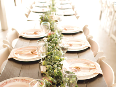 wood table set with elegant plates with pink and green elements.